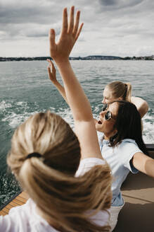 Cheerful female friends on a boat trip on a lake - LHPF00894