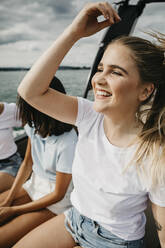 Glückliche junge Frau mit Freunden bei einer Bootsfahrt auf einem See - LHPF00895