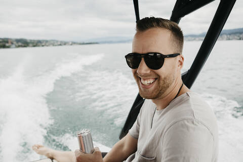 Glücklicher Mann mit Sonnenbrille bei einer Bootsfahrt auf einem See, lizenzfreies Stockfoto