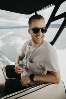 Happy man wearing sunglasses on a boat trip on a lake stock photo