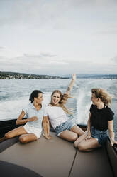 Glückliche Freundinnen, die sich bei einer Bootsfahrt auf einem See amüsieren - LHPF00952