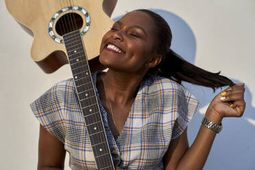 Happy woman holding a guitar on her shoulder - VEGF00715