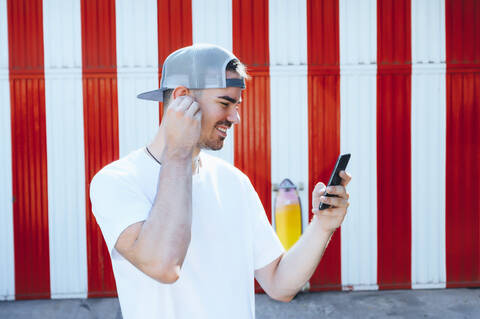 Lächelnder junger Mann mit Smartphone in der Stadt, lizenzfreies Stockfoto