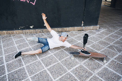 Amputierter junger Mann hat Spaß mit Beinprothese und Skateboard - JCMF00240