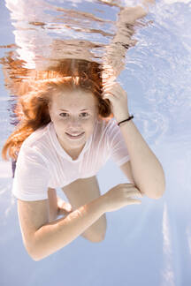 Portrait of teenage girl wearing t-shirt diving under water stock photo