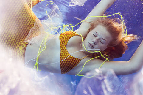 Teenager-Nixe, umgeben von Abfall unter Wasser, lizenzfreies Stockfoto