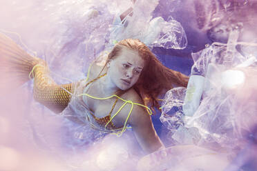 Teenage mermaid girl surrounded by plastic waste under water - STBF00401