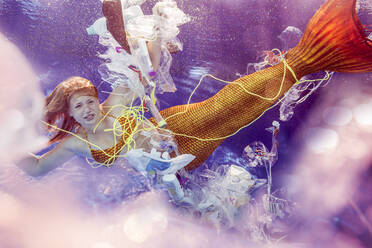 Teenage mermaid girl surrounded by plastic waste under water - STBF00403