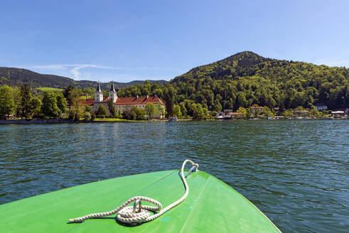 Boot auf dem See mit Kloster Tegernsee und St. Quirinus Kirche im Hintergrund gegen blauen Himmel in Bayern, Deutschland - LHF00720