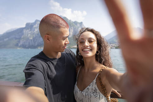 Junges Paar macht ein Selfie vor dem Comer See, Lecco, Italien - MCVF00049