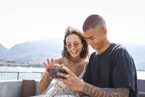 Glückliches junges Paar, das auf sein Handy schaut, Lecco, Italien, lizenzfreies Stockfoto