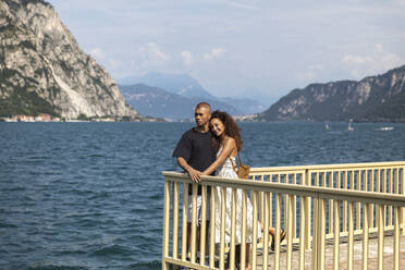 Glückliches junges Paar auf einer Terrasse vor dem Comer See, Lecco, Italien - MCVF00055