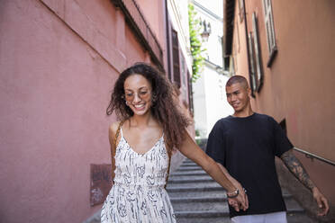 Portrait of happy young woman walking on alley with her boyfriend, Lecco, Italy - MCVF00056