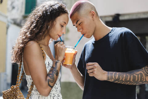 Junges Paar trinkt gemeinsam Fruchtsaft, lizenzfreies Stockfoto