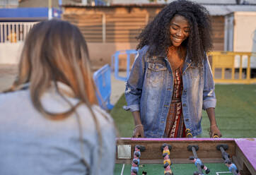 Portrait of happy young woman playing table football with her friend - VEGF00722