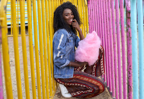 Porträt einer glücklichen jungen Frau mit rosa Zuckerwatte auf dem Jahrmarkt, lizenzfreies Stockfoto