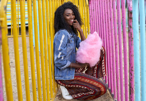 Porträt einer glücklichen jungen Frau mit rosa Zuckerwatte auf dem Jahrmarkt - VEGF00732
