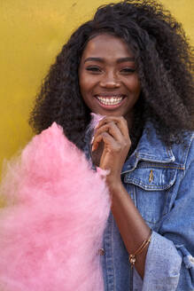 Porträt einer glücklichen jungen Frau mit rosa Zuckerwatte - VEGF00737