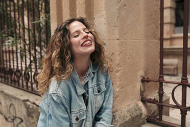 Happy young woman with curly hair and glasses in the city - LOTF00076