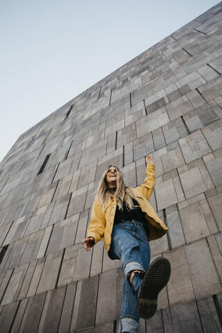 Lachende junge Frau, die auf einem Bein balanciert, Wien, Österreich, lizenzfreies Stockfoto