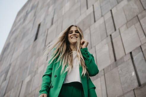 Portrait of laughing young woman wearing green pantsuit, Vienna, Austria - LHPF00981