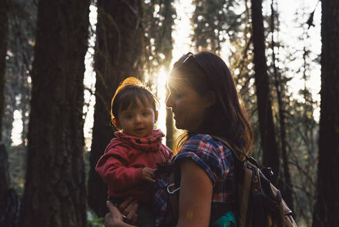 Mutter hält ein kleines Mädchen im Wald bei Sonnenuntergang im Sequoia National Park, Kalifornien, USA - GEMF03175