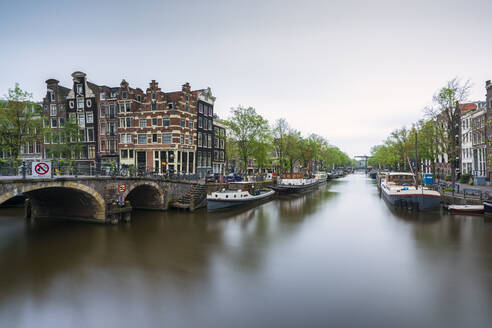 Netherlands, Amsterdam, Arch bridge over city canal with boats moored in background - XCF00227