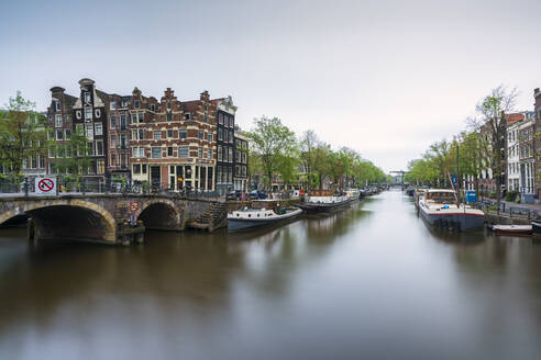 Niederlande, Amsterdam, Bogenbrücke über den Stadtkanal mit ankernden Booten im Hintergrund - XCF00227
