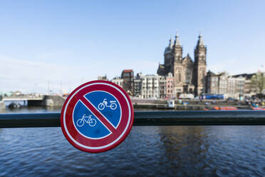 Niederlande, Amsterdam, Fahrradverbotsschild am Geländer mit der Basilika St. Nikolaus im Hintergrund - XCF00233