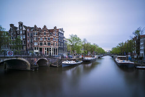 Netherlands, Amsterdam, Arch bridge over city canal with boats moored in background - XCF00236