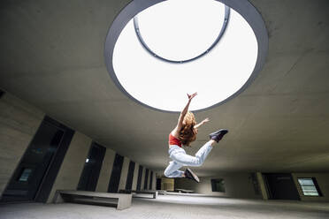 Sporty young woman jumping in courtyard - JSM01273