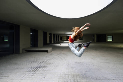 Sporty young woman jumping in courtyard - JSM01274