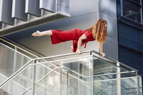 Sporty young woman doing acrobatics on a railing - JSMF01279