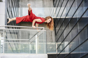 Sportliche junge Frau macht Akrobatik auf einem Geländer - JSMF01280
