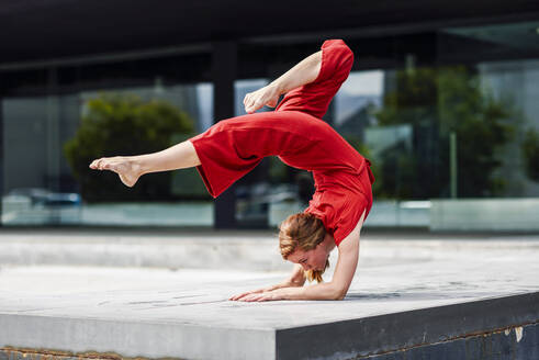 Sportliche junge Frau macht Akrobatik im Freien - JSMF01287