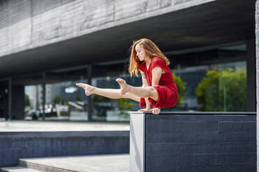 Sportliche junge Frau macht Akrobatik an einer Wand - JSMF01289