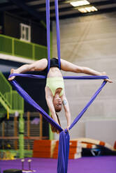 Junge Frau macht Aerial Silk in einem Übungsraum - JSMF01299