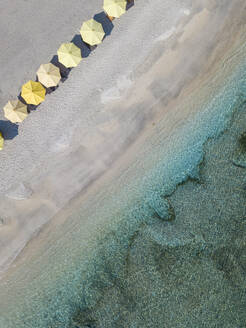 Drohnenansicht von gelben Sonnenschirmen am Strand von Bali, Indonesien - KNTF03490