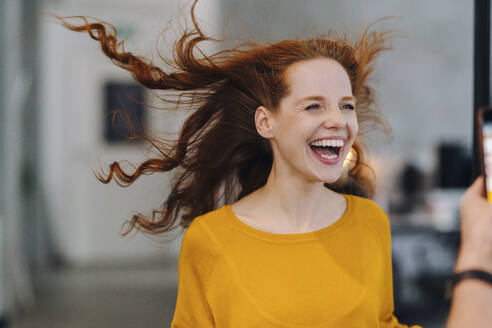 Laughing woman with windswept hair in office - KNSF06586