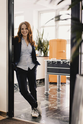 Porträt einer lächelnden rothaarigen Geschäftsfrau im Büro, lizenzfreies Stockfoto