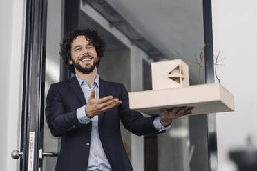 Happy architect in office holding architectural model - KNSF06602