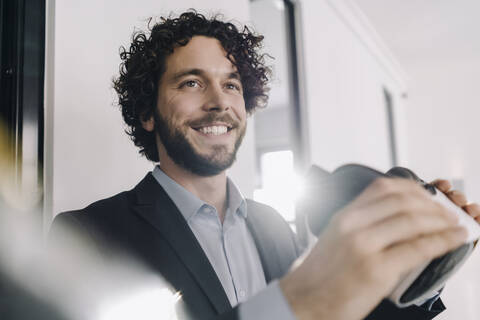 Porträt eines lächelnden Geschäftsmannes mit VR-Brille im Büro, lizenzfreies Stockfoto