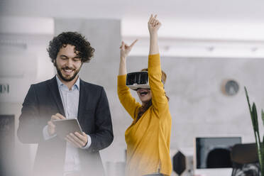 Happy businessman and businesswoman with VR glasses and tablet in office - KNSF06606