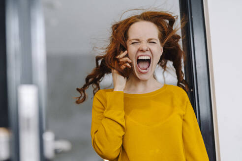 Screaming woman with windswept hair in office - KNSF06607