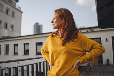 Rothaarige Frau auf Dachterrasse stehend - KNSF06616