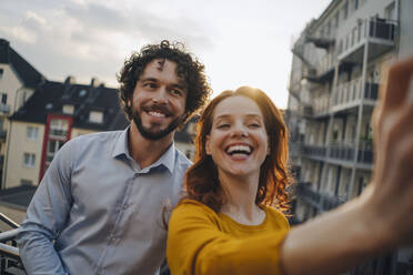 Zwei glückliche Kollegen auf der Dachterrasse machen ein Selfie - KNSF06619