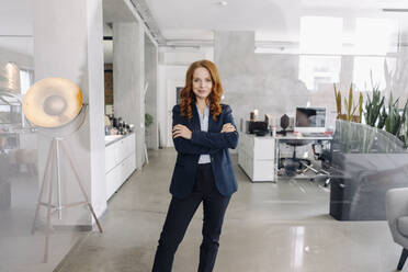 Porträt einer selbstbewussten rothaarigen Geschäftsfrau, die in einem Büro steht - KNSF06633