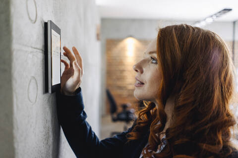 Geschäftsfrau benutzt Gerät an einer Wand, lizenzfreies Stockfoto