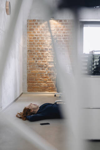 Müde Geschäftsfrau auf dem Boden liegend im Büro, lizenzfreies Stockfoto