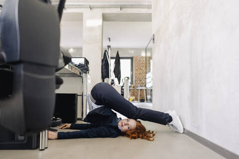 Geschäftsfrau auf dem Boden liegend im Büro beim Sport, lizenzfreies Stockfoto